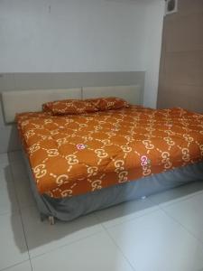 a bed with an orange comforter on top of it at Rubikz Hostel & Cafe in Surabaya