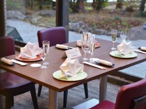 Hotel New Gaea Omuta Garden في Ōmuta: طاولة خشبية بها صحون واكواب ومناديل للنبيذ