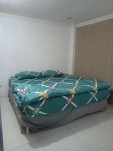 a bed with a blue comforter on top of it at Rubikz Hostel & Cafe in Surabaya