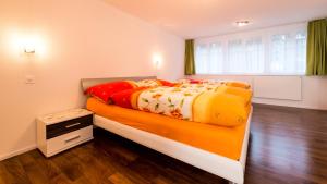 a bedroom with a bed with colorful sheets and a window at Bergheimat in Saas-Almagell