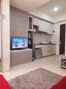 a living room with a television and a kitchen at Apartement Grand Asia Afrika Residence Bandung in Bandung