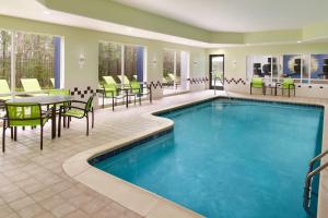 a pool in a hotel room with tables and chairs at SpringHill Suites Raleigh-Durham Airport/Research Triangle Park in Durham