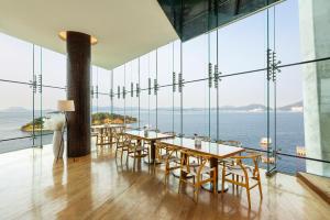 Hidden Bay Hotel في يوسو: غرفة بها طاولات وكراسي ومطلة على المحيط