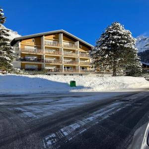 um grande edifício com neve em frente a uma estrada em mountain bliss & hot springs em Leukerbad