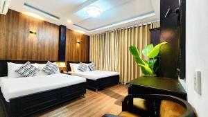 a hotel room with two beds and a plant at Rosa May Hotel in Ho Chi Minh City