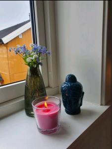 a candle and a vase with flowers on a window sill at Fantastic and high standard apartment in Nordseter in Lillehammer