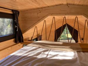 a bed in a log cabin with a window at Roque Rouge Cottage by Tiny Away in Bédarieux