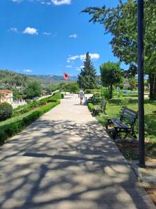 a man walking down a path in a park with benches at Aleko Guesthouse in Përmet