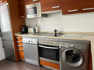 a kitchen with a washing machine and a microwave at Apartamento familiar Azucar en Llanes in Llanes