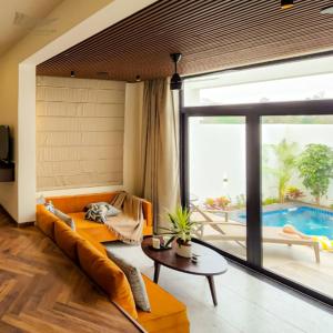 sala de estar con sofá naranja y piscina en The Golden Tusk By Ivory Destinations, en Rāmnagar