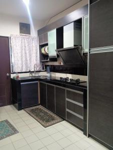 cocina con armarios negros, fregadero y ventana en Salak Indah Homestay KLIA/KLIA2, en Sepang