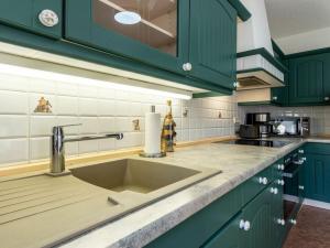 a kitchen with green cabinets and a sink at Fire Comfortable holiday residence in Ostseebad Koserow