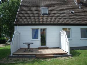 a small white house with a table on a wooden deck at Picobello 2 Comfortable holiday residence in Timmendorfer Strand +7 photos