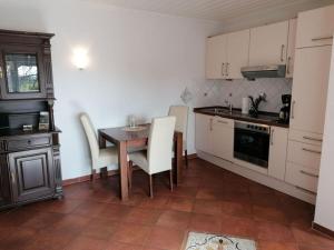 una cucina con tavolo, mobili bianchi, tavolo e sedie di Deichjuwel Comfortable holiday residence a Norddeich