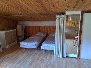 two beds in a room with wooden walls and wood floors at Joli appartement in Valdeblore