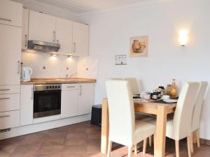 cocina con mesa de madera y armarios blancos en Windrose Comfortable holiday residence en Norddeich