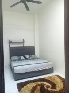 Salak Indah Homestay KLIA/KLIA2 في سيبانغ: غرفة نوم بسرير مع مروحة سقف وسجادة