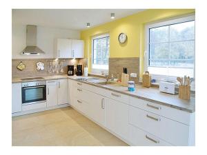 una cucina con mobili bianchi e un orologio sul muro di Seewind Comfortable holiday residence a Breege