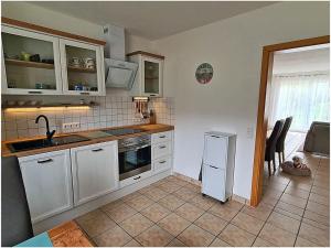 ブレーゲにあるPatricia Comfortable holiday residenceのタイルフロアのキッチン(白いキャビネット付)