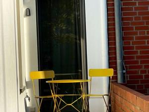duas cadeiras amarelas sentadas do lado de fora de uma janela em Mooi 3 Comfortable holiday residence em Norderney