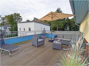 a patio with chairs and an umbrella on a deck at Penthouse Sea Breeze in Juliusruh
