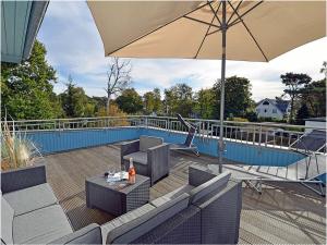 a patio with a table and an umbrella on a deck at Penthouse Sea Breeze in Juliusruh
