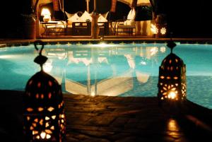 ein Schwimmbad in der Nacht mit Lichtern im Wasser in der Unterkunft Ecolodge Bab El Oued Maroc Oasis in Agdz