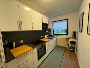 una cocina con armarios blancos y una ventana en Lovely apartment near the water en Weilburg