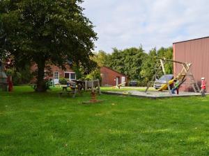 um parque com um parque infantil com um baloiço em Farmhouse Comfortable holiday residence em Norddeich