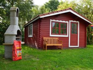una pequeña casa roja con un banco en el césped en Farmhouse Comfortable holiday residence, en Norddeich