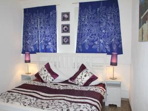 um quarto com cortinas azuis e uma cama com almofadas em Vulkaneifel Comfortable holiday residence em Daun