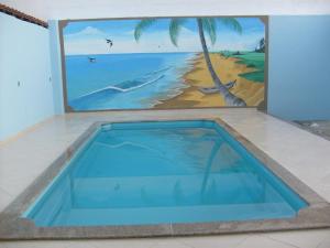 una piscina en una habitación con una pintura en la pared en Pousada Barra Mares, en Mucuri