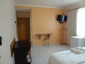 a room with a desk and a bed and a table at Pousada Barra Mares in Mucuri