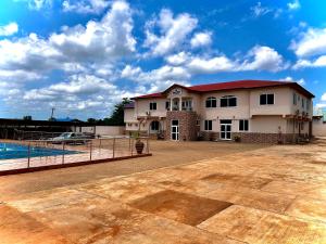 uma grande casa branca com um telhado vermelho em Jessie Hotel em Apenkwa