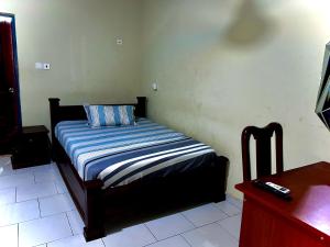 uma pequena cama num quarto com controlo remoto em Jessie Hotel em Apenkwa