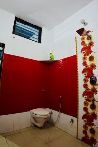 a bathroom with a toilet and a red wall at BLISS STAYS in Rishīkesh