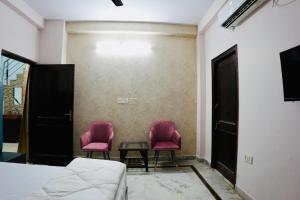 two pink chairs in a room with a bed and a table at BLISS STAYS in Rishīkesh