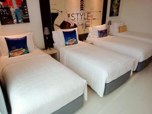 drie bedden in een kamer met witte lakens en blauwe kussens bij Hotel Clover Asoke - SHA Extra Plus in Bangkok