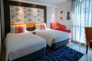 a hotel room with two beds and a chair at Hotel Clover Asoke - SHA Extra Plus in Bangkok