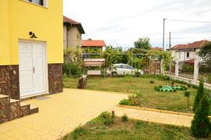 un cortile con una casa gialla e un giardino di Guest House Nocturno a Berkovica