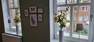 Deux vases avec des fleurs dans une pièce avec des fenêtres dans l'établissement Ferienwohnung am Bibelgarten Sophia, à Werlte