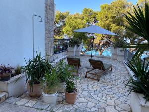 a patio with an umbrella and chairs and plants at Apartman Ratac 11 in Tučepi