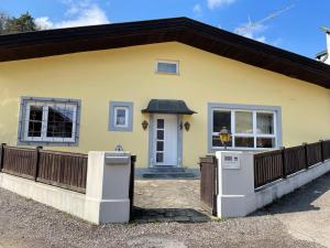 a yellow house with a wooden fence in front of it at Ferienhaus Schneeweiß in Senftenberg