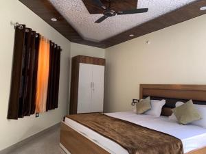 Schlafzimmer mit einem Bett und einem Deckenventilator in der Unterkunft Goroomgo Tapovan Residency Haridwar - Excellent Service Recommended in Haridwar