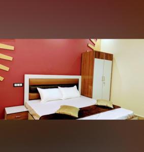 ein Schlafzimmer mit einem Bett mit einer roten Wand in der Unterkunft Goroomgo Tapovan Residency Haridwar - Excellent Service Recommended in Haridwar