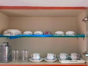 a shelf with cups and saucers on it at Kailash Guest Home in Mysore