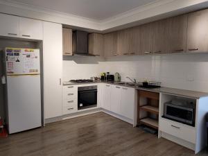 a kitchen with white appliances and wooden cabinets at Wollert Ground Floor Entire Apartment- Close to Melbourne Airport-Free WIFI-Washer & Dryer in Wollert
