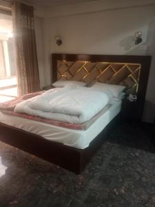 a bed in a bedroom with a wooden headboard at AL KHALEEJ HOTEL in Murree