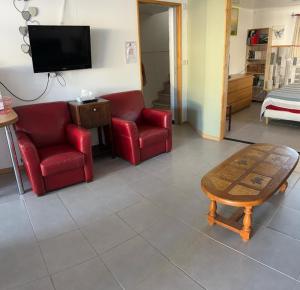 een woonkamer met 2 rode stoelen en een salontafel bij B & B Florence et Francis in Cuxac-dʼAude
