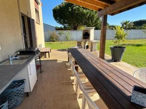 - un banc en bois sur une terrasse avec barbecue dans l'établissement B & B Florence et Francis, à Cuxac-dʼAude